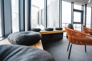 Detailblick in die Lounge auf die Holzbank direkt am Fenster mit gemütlichen Sitzpolstern.