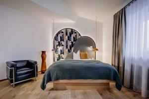 cleanes Hotelzimmer mit hochwertigem Holzboden, kunstvollen Tapetenelementen, gemachtem Doppelbett